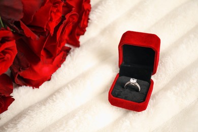 Photo of Dreams come true. Beautiful engagement ring in box and flowers on light plaid, closeup