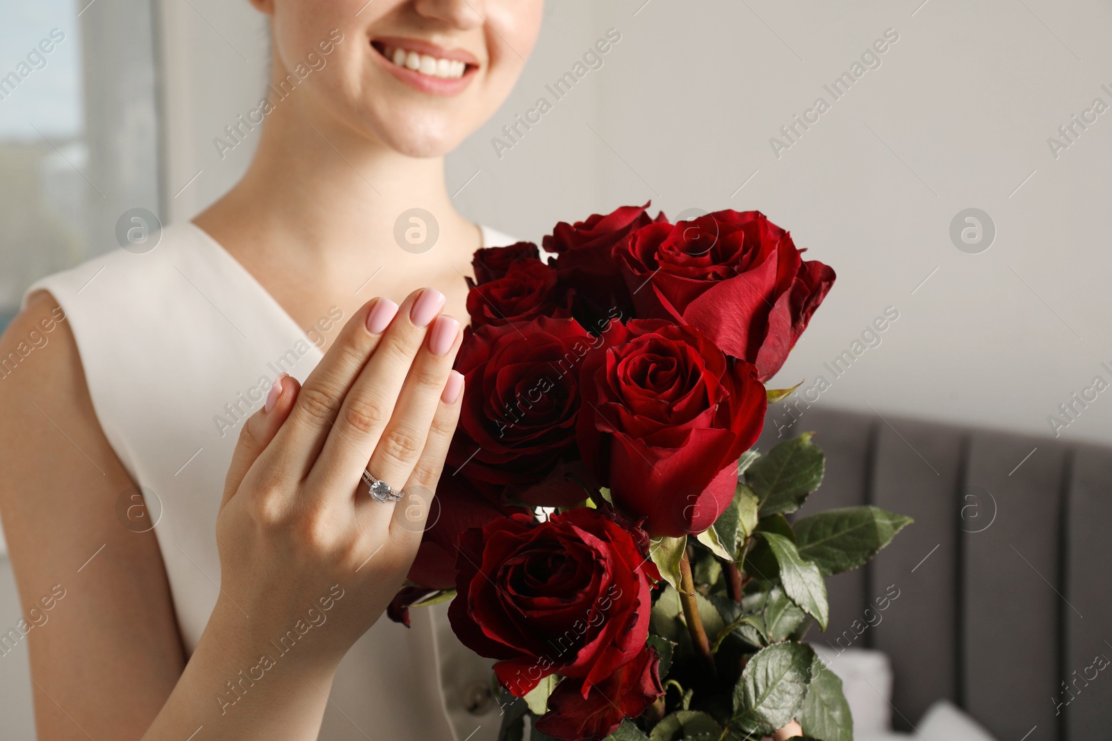 Photo of Dreams come true. Happy woman with engagement ring and beautiful bouquet indoors, closeup