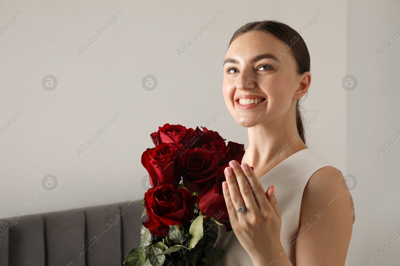 Photo of Dreams come true. Happy woman with engagement ring and beautiful bouquet indoors. Space for text