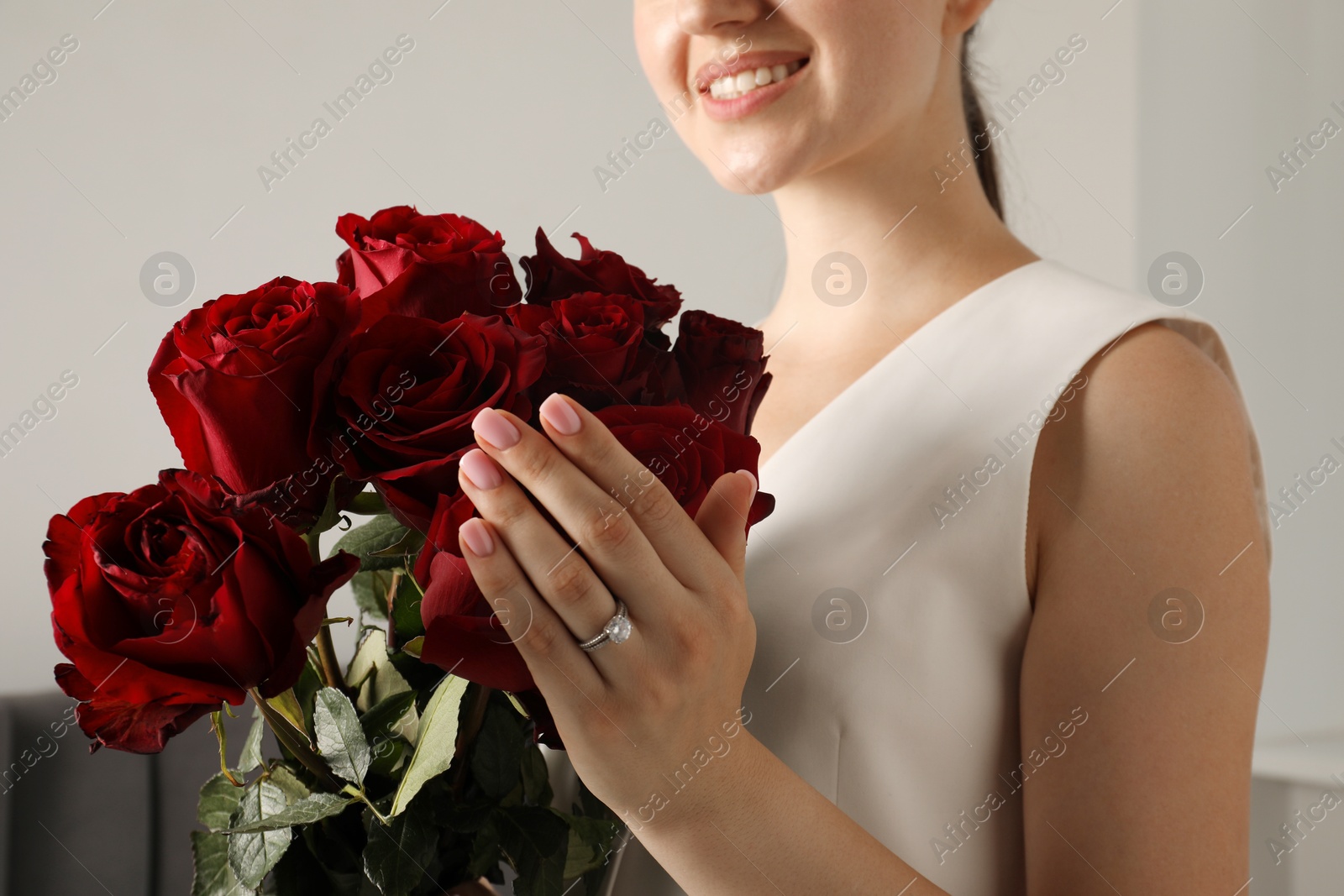 Photo of Dreams come true. Happy woman with engagement ring and beautiful bouquet indoors, closeup