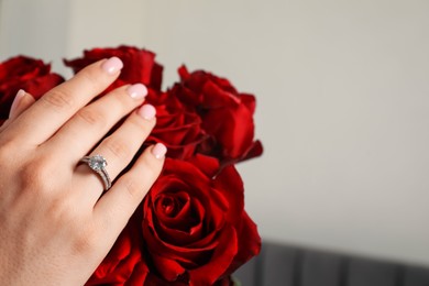 Photo of Dreams come true. Happy woman with engagement ring and beautiful bouquet indoors, closeup. Space for text