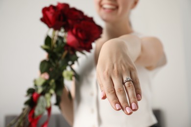 Photo of Dreams come true. Happy woman with engagement ring and beautiful bouquet indoors, closeup