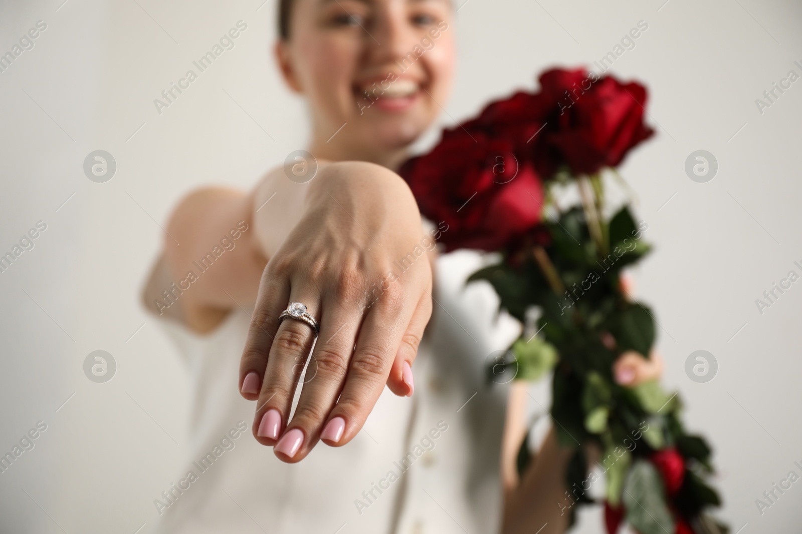 Photo of Dreams come true. Happy woman with engagement ring and beautiful bouquet indoors, selective focus