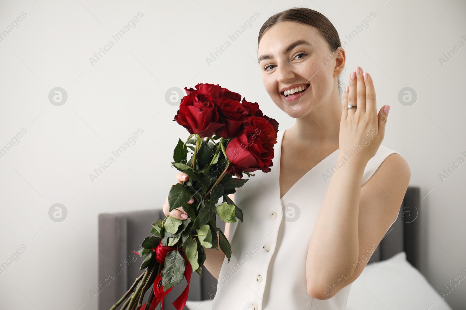 Photo of Dreams come true. Happy woman with engagement ring and beautiful bouquet indoors