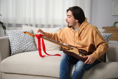 Photo of Dreams come true. Excited man with guitar at home, space for text