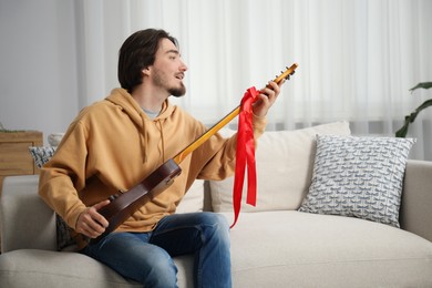 Photo of Dreams come true. Excited man with guitar at home, space for text