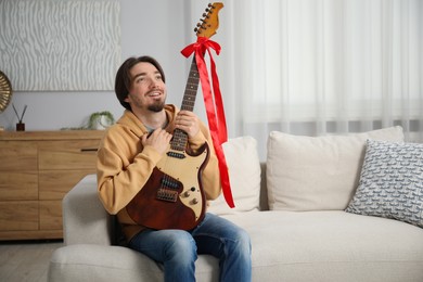 Photo of Dreams come true. Happy man with guitar at home, space for text