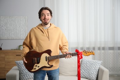 Photo of Dreams come true. Happy man with guitar at home, space for text