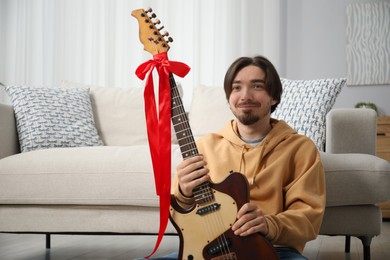 Photo of Dreams come true. Happy man with guitar at home, space for text