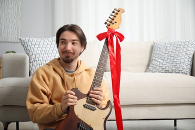 Photo of Dreams come true. Happy man with guitar at home, space for text