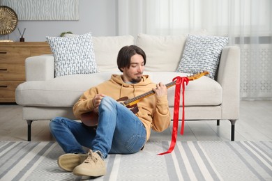 Photo of Dreams come true. Happy man with guitar at home