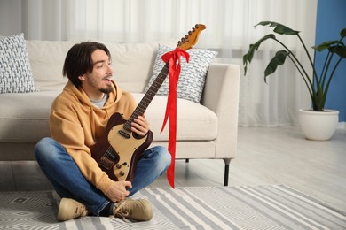 Photo of Dreams come true. Excited man with guitar at home, space for text