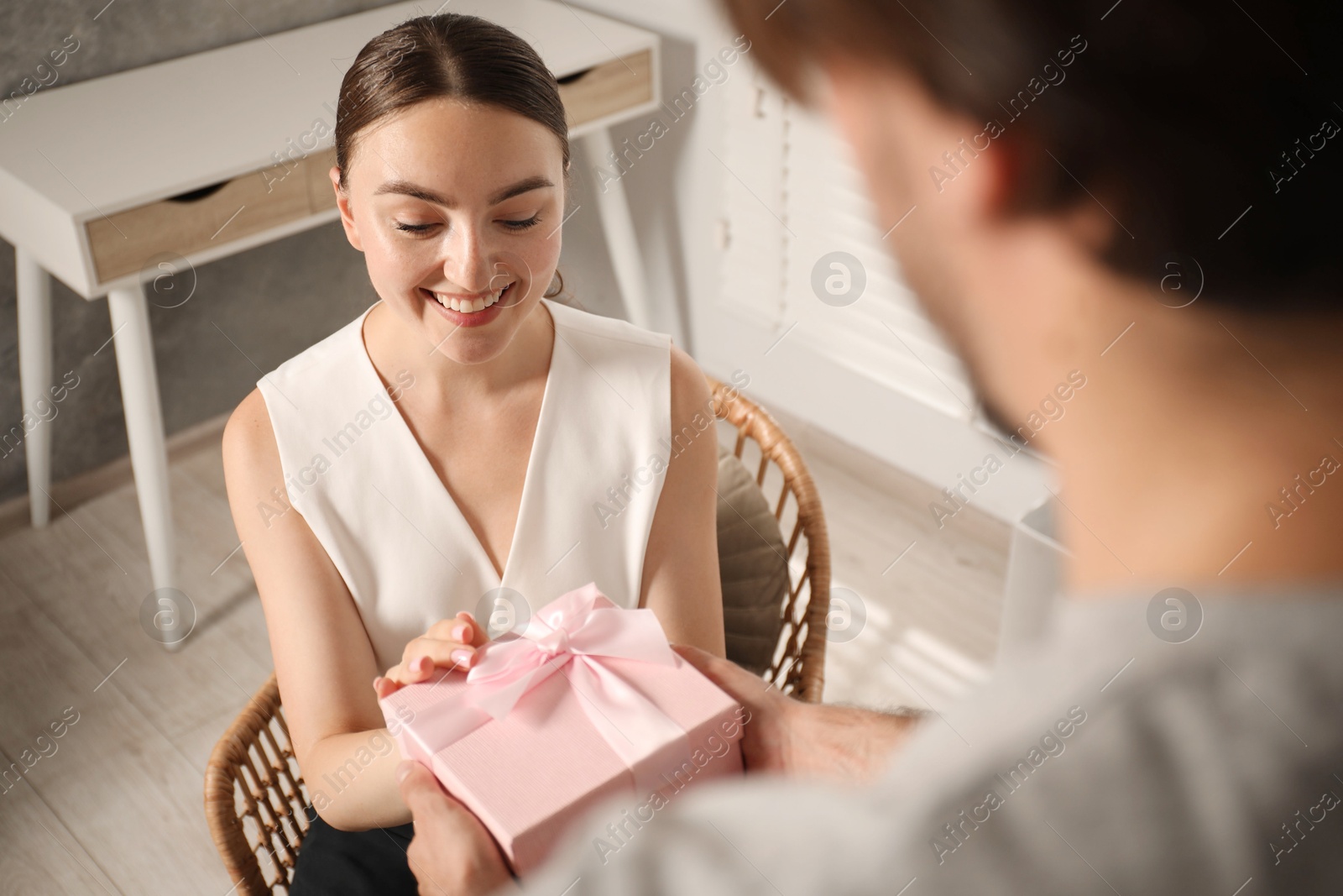 Dreams come true. Man surprising woman with gift at home, closeup Photo of Dreams come true. Man surprising woman with gift at home, closeup