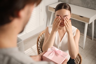 Photo of Dreams come true. Man surprising woman with gift at home, closeup