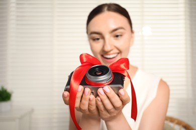 Photo of Dreams come true. Woman with new gifted camera at home, selective focus