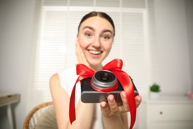 Photo of Dreams come true. Woman with new gifted camera at home, selective focus