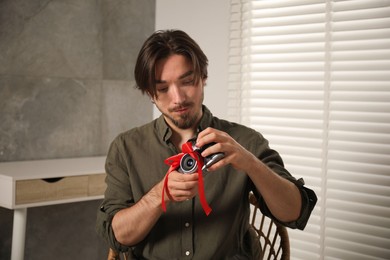 Photo of Dreams come true. Man with new gifted camera at home