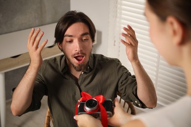 Photo of Dreams come true. woman gifting man camera at home, closeup