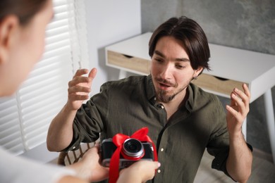 Photo of Dreams come true. woman gifting man camera at home, closeup