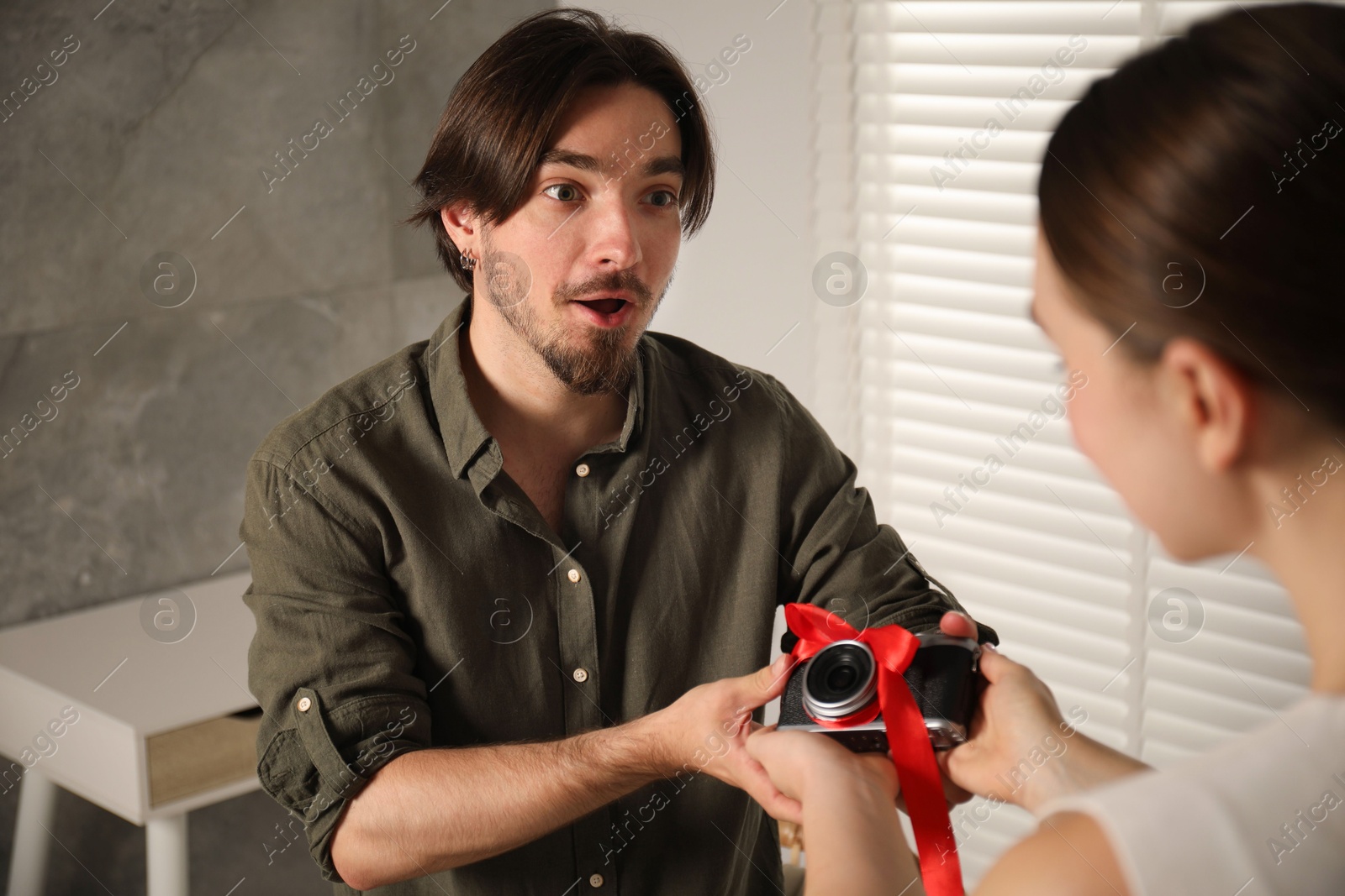Photo of Dreams come true. woman gifting man camera at home, closeup