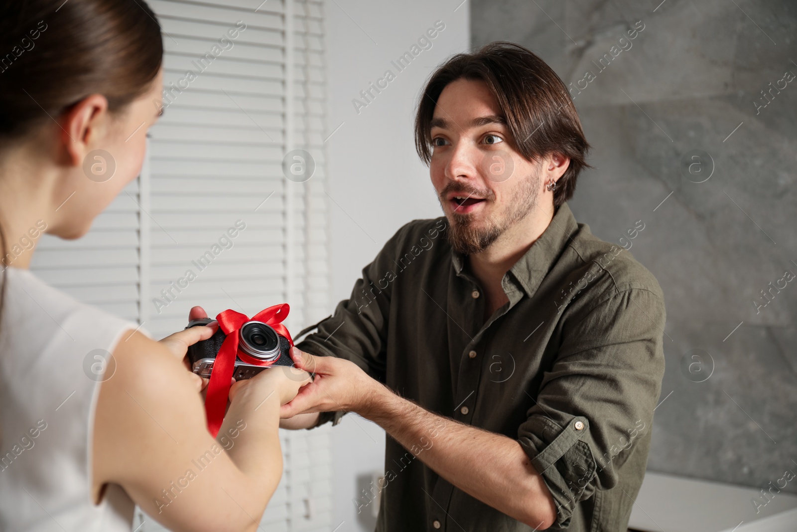 Photo of Dreams come true. woman gifting man camera at home, closeup