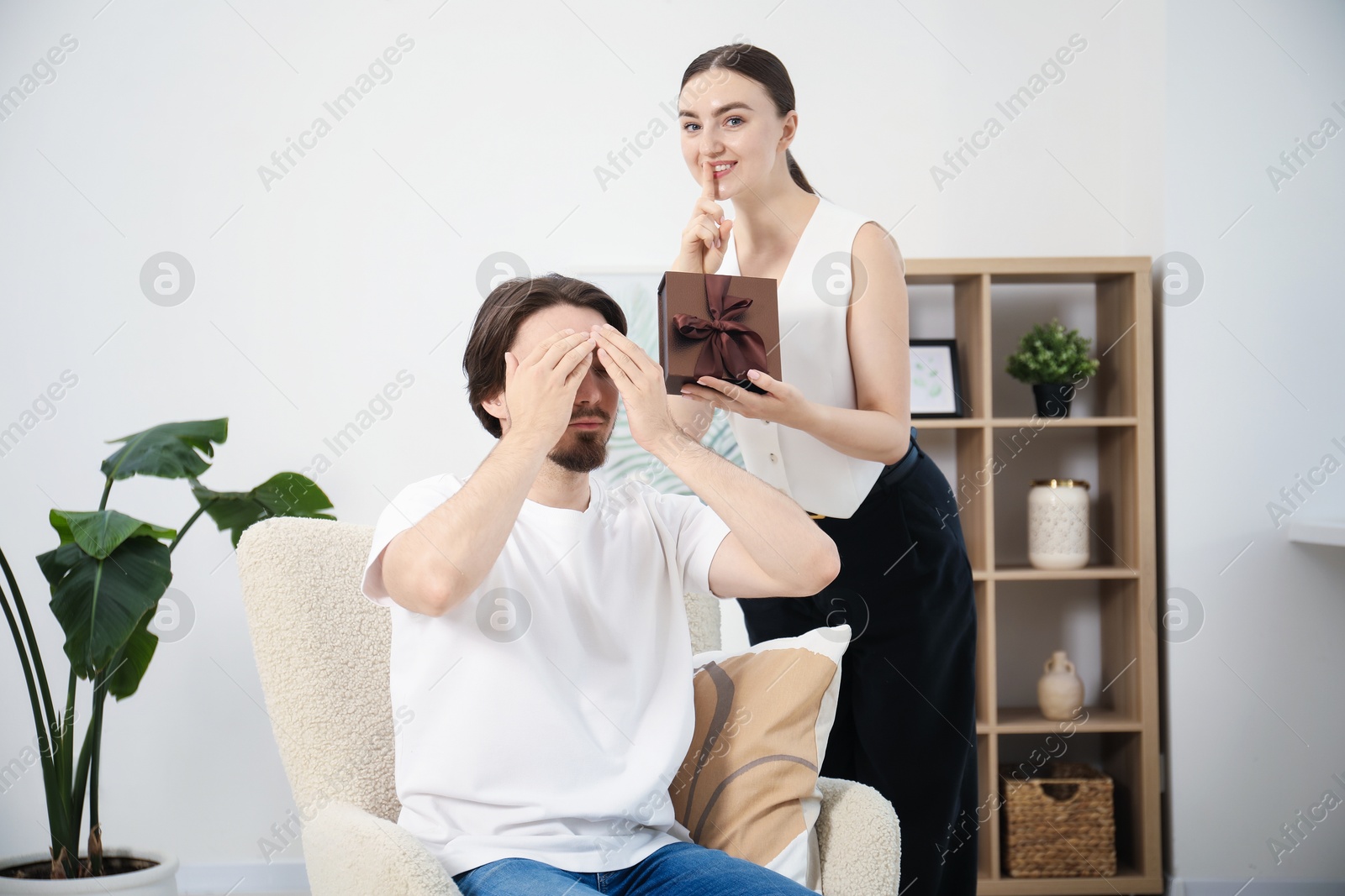 Dreams come true. Woman giving man gift box at home Photo of Dreams come true. Woman giving man gift box at home