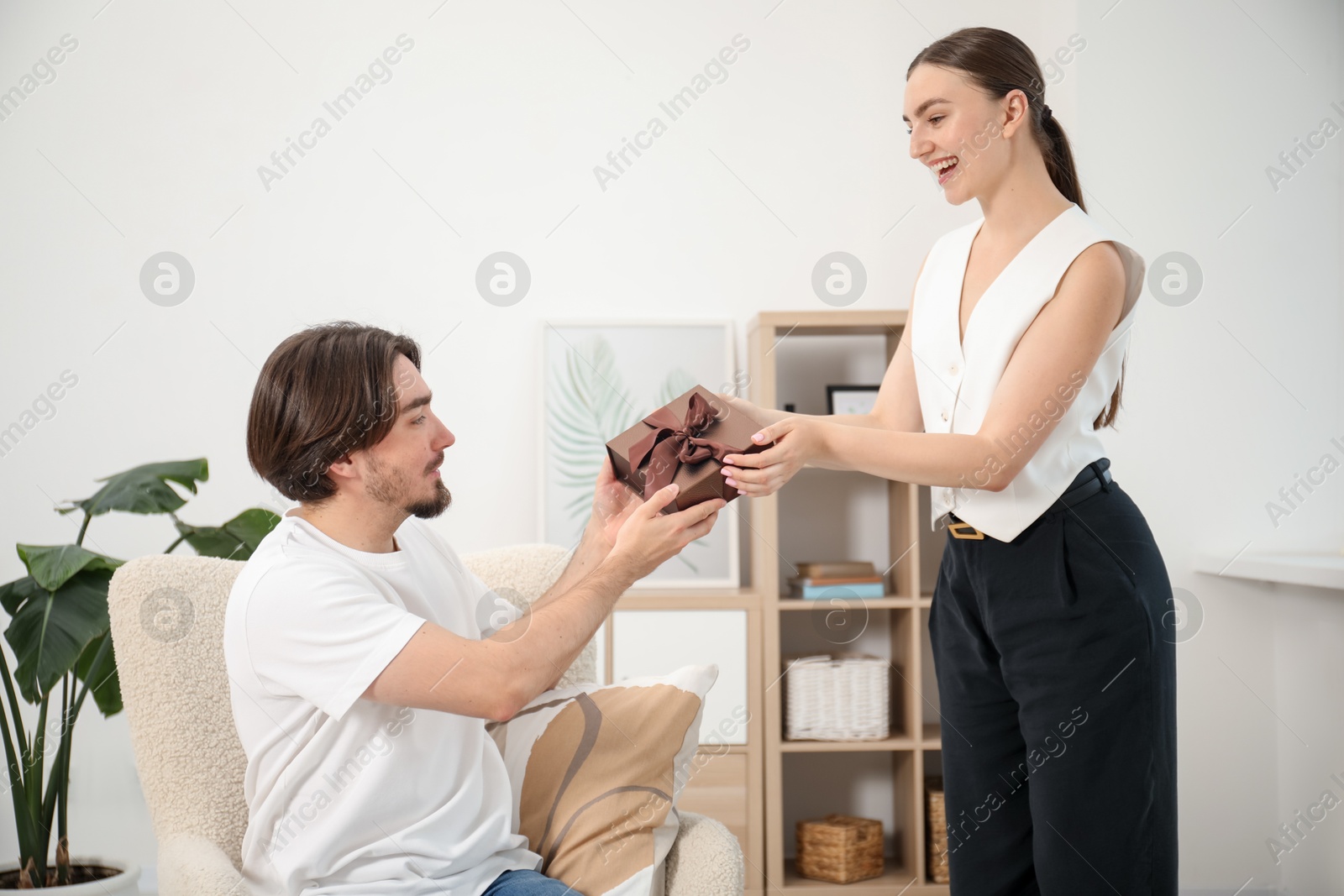 Dreams come true. Woman giving man gift box at home Photo of Dreams come true. Woman giving man gift box at home