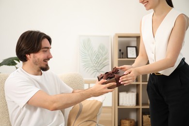 Photo of Dreams come true. Woman giving man gift box at home, closeup