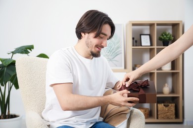 Photo of Dreams come true. Woman giving man gift box at home, closeup