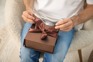 Photo of Dreams come true. Man with gift at home, closeup