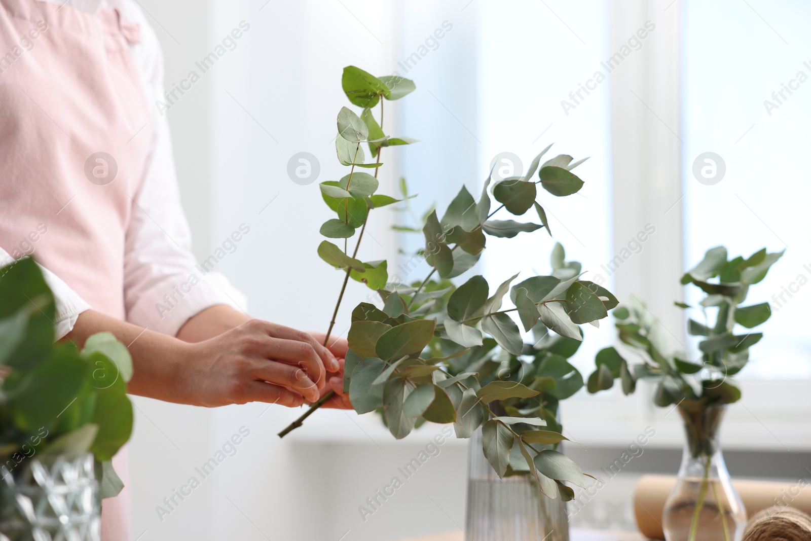 Florist making beautiful bouquet of eucalyptus branches in flower shop, closeup Photo of Florist making beautiful bouquet of eucalyptus branches in flower shop, closeup