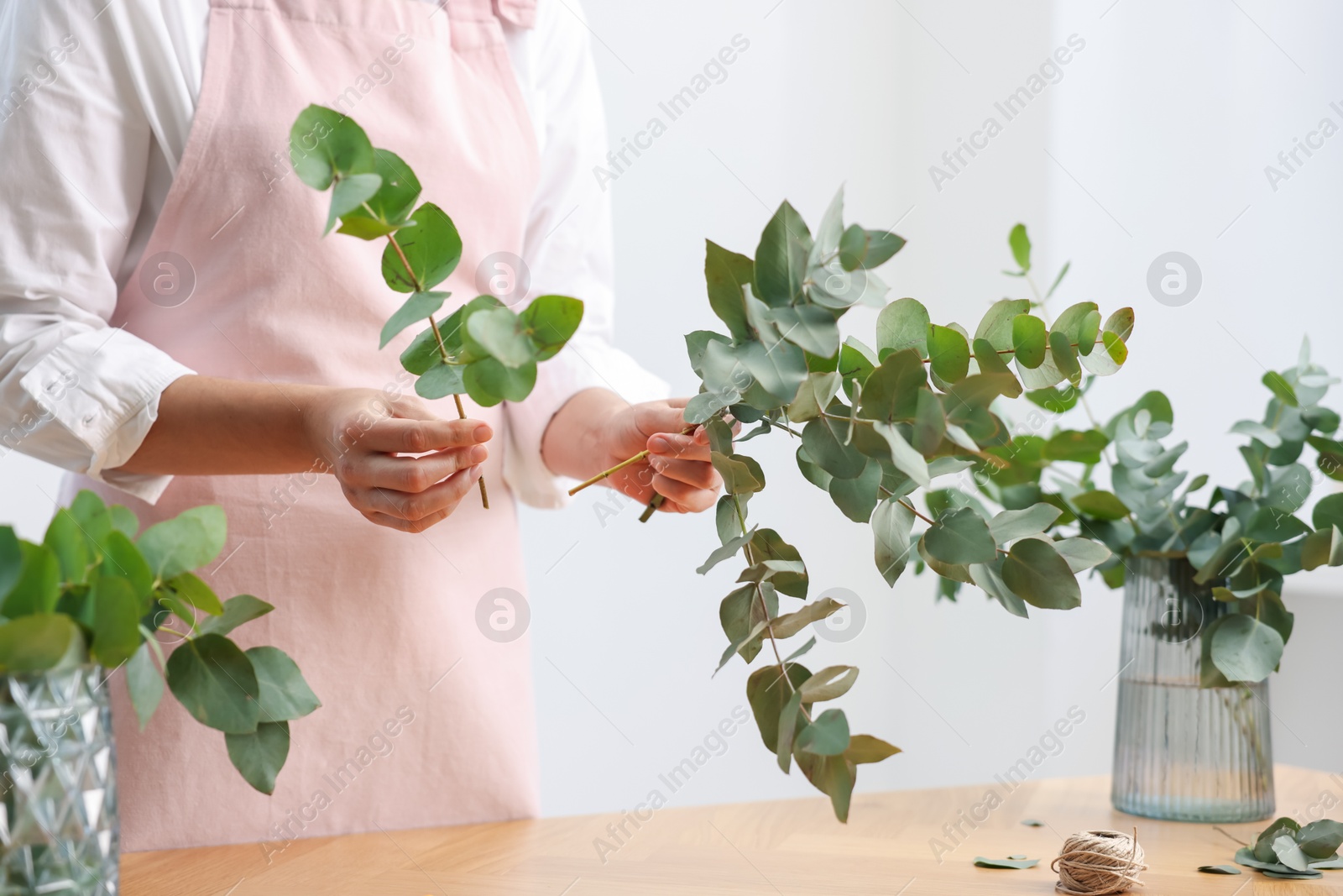 Florist making beautiful bouquet of eucalyptus branches at wooden table in flower shop, closeup Photo of Florist making beautiful bouquet of eucalyptus branches at wooden table in flower shop, closeup