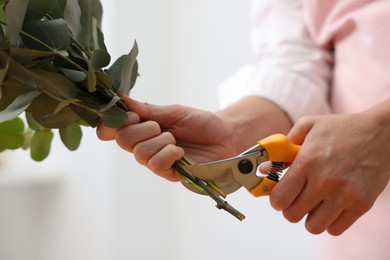 Photo of Florist making beautiful bouquet of eucalyptus branches in flower shop, closeup