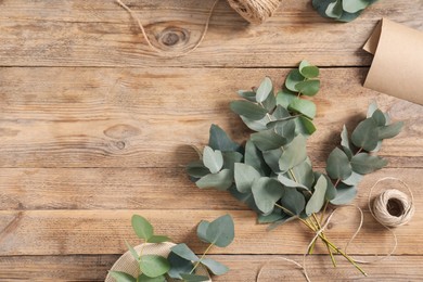 Photo of Florist. Eucalyptus branches, thread and wrapping paper on wooden table, flat lay. Space for text