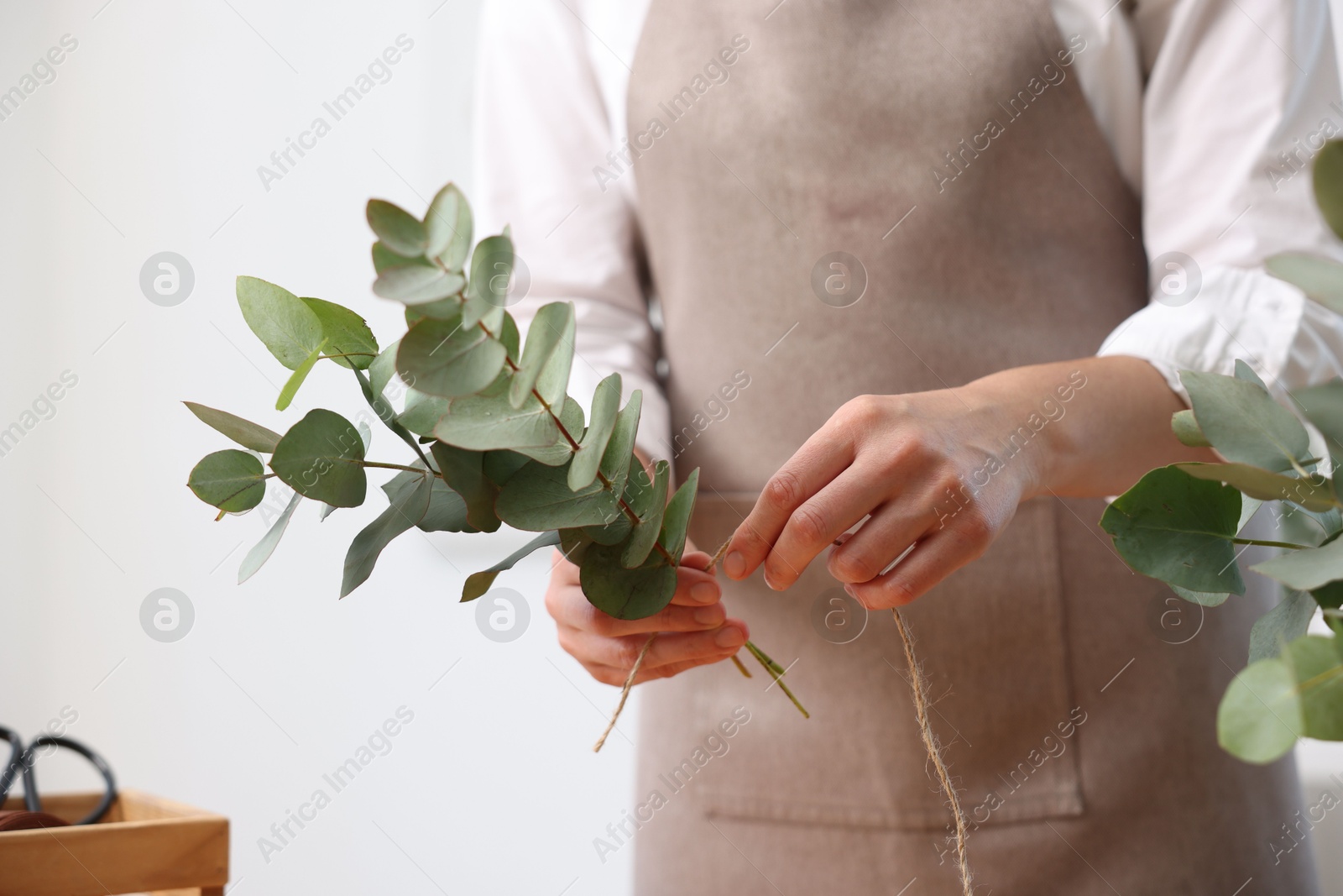 Florist making beautiful bouquet of eucalyptus branches in flower shop, closeup Photo of Florist making beautiful bouquet of eucalyptus branches in flower shop, closeup
