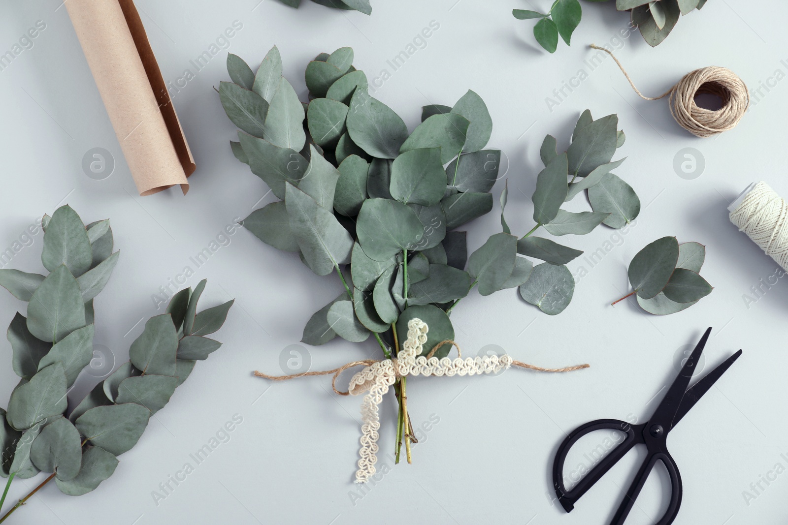 Florist. Eucalyptus branches, threads, wrapping paper and scissors on white table, flat lay Photo of Florist. Eucalyptus branches, threads, wrapping paper and scissors on white table, flat lay