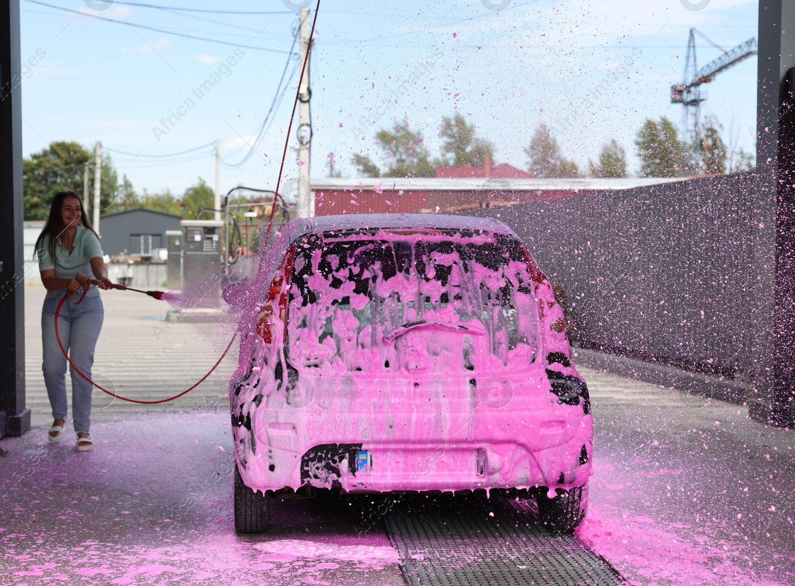 Photo of Woman washing auto with foam at car wash