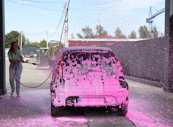 Photo of Woman washing auto with foam at car wash