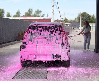 Photo of Woman washing auto with foam at car wash