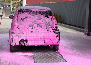 Photo of Auto covered with cleaning foam at outdoor car wash