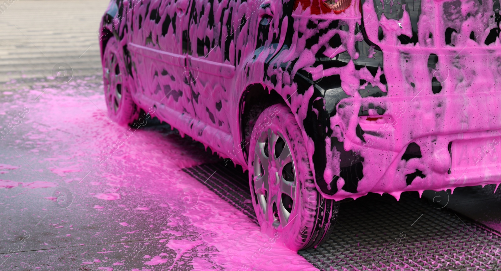 Photo of Auto covered with cleaning foam at outdoor car wash, closeup