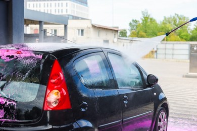 Photo of Washing auto with high pressure water jet at car wash, closeup