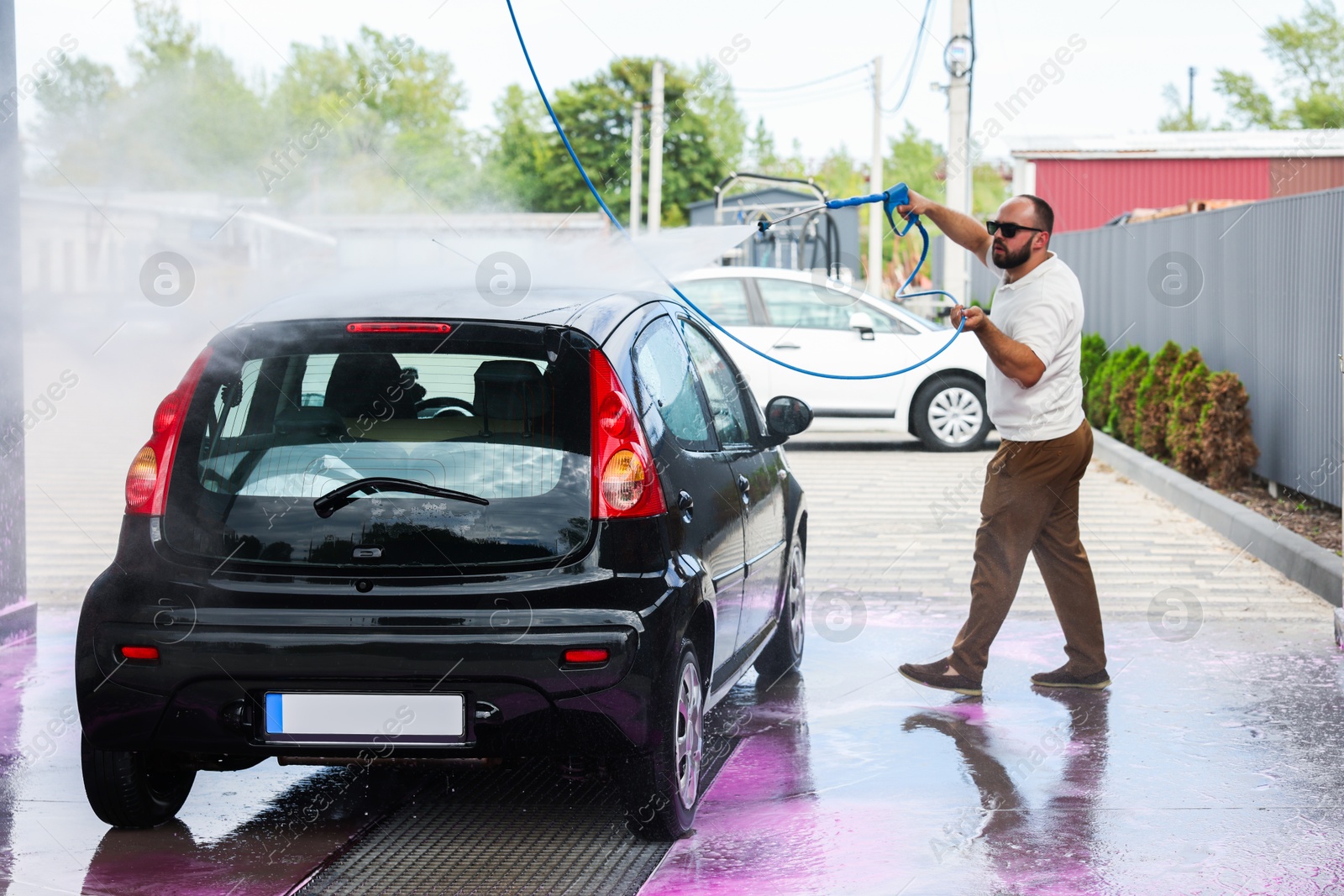 Man washing auto with high pressure water jet at car wash Photo of Man washing auto with high pressure water jet at car wash