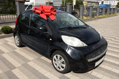 Photo of Dreams come true. New auto with big red bow outdoors