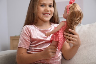 Photo of Dreams come true. Cute little girl with beautiful doll on sofa at home