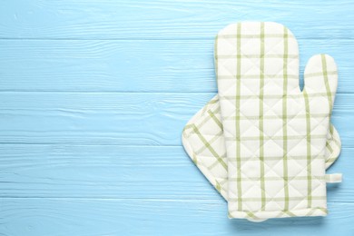 Photo of Oven glove and potholder on light blue wooden background, top view. Space for text
