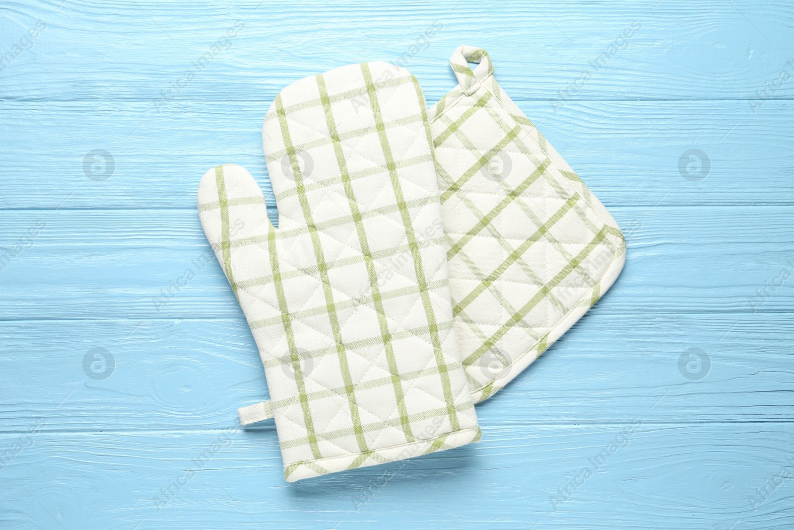 Oven glove and potholder on light blue wooden background, flat lay Photo of Oven glove and potholder on light blue wooden background, flat lay