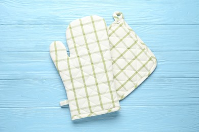 Photo of Oven glove and potholder on light blue wooden background, flat lay