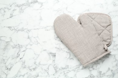 Photo of Oven glove and potholder on white marble table, flat lay. Space for text