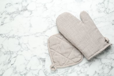 Photo of Oven glove and potholder on white marble table, flat lay. Space for text